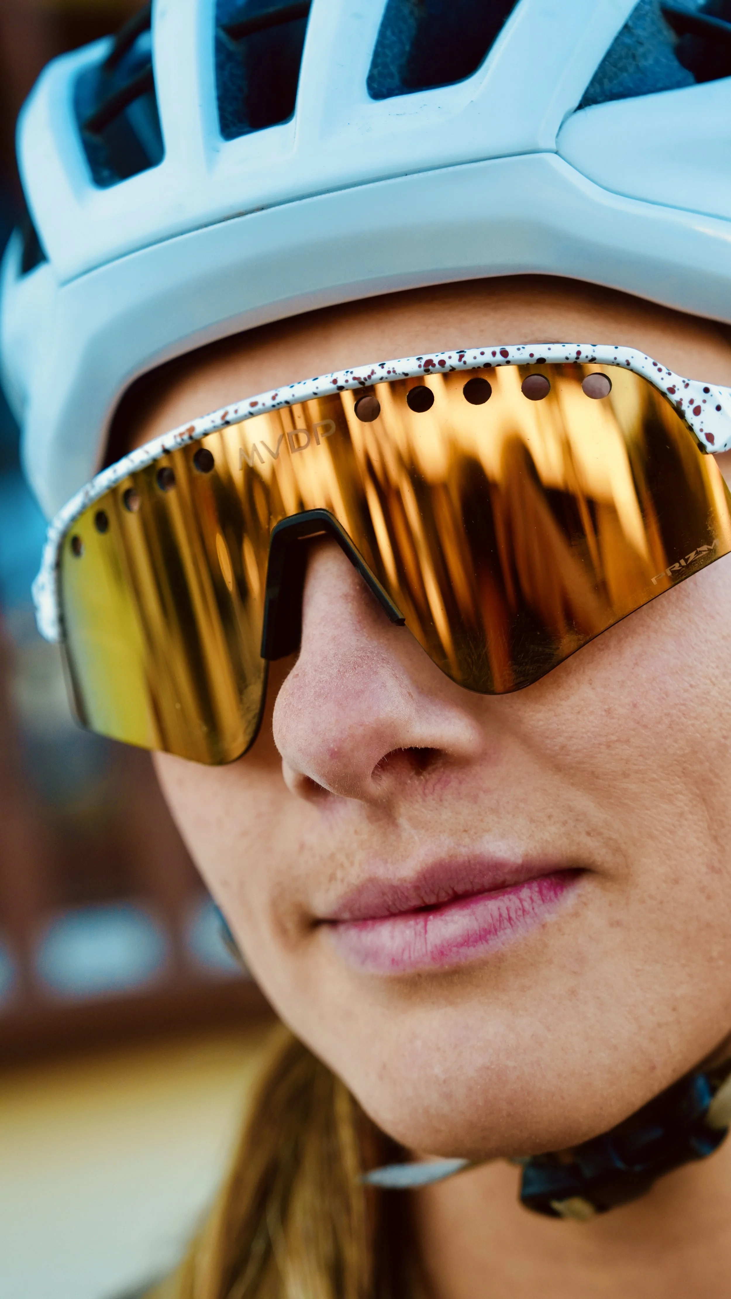 Close-up of a person's face wearing a blue helmet and reflective yellow goggles, with a focus on the goggles and part of their nose and lips.