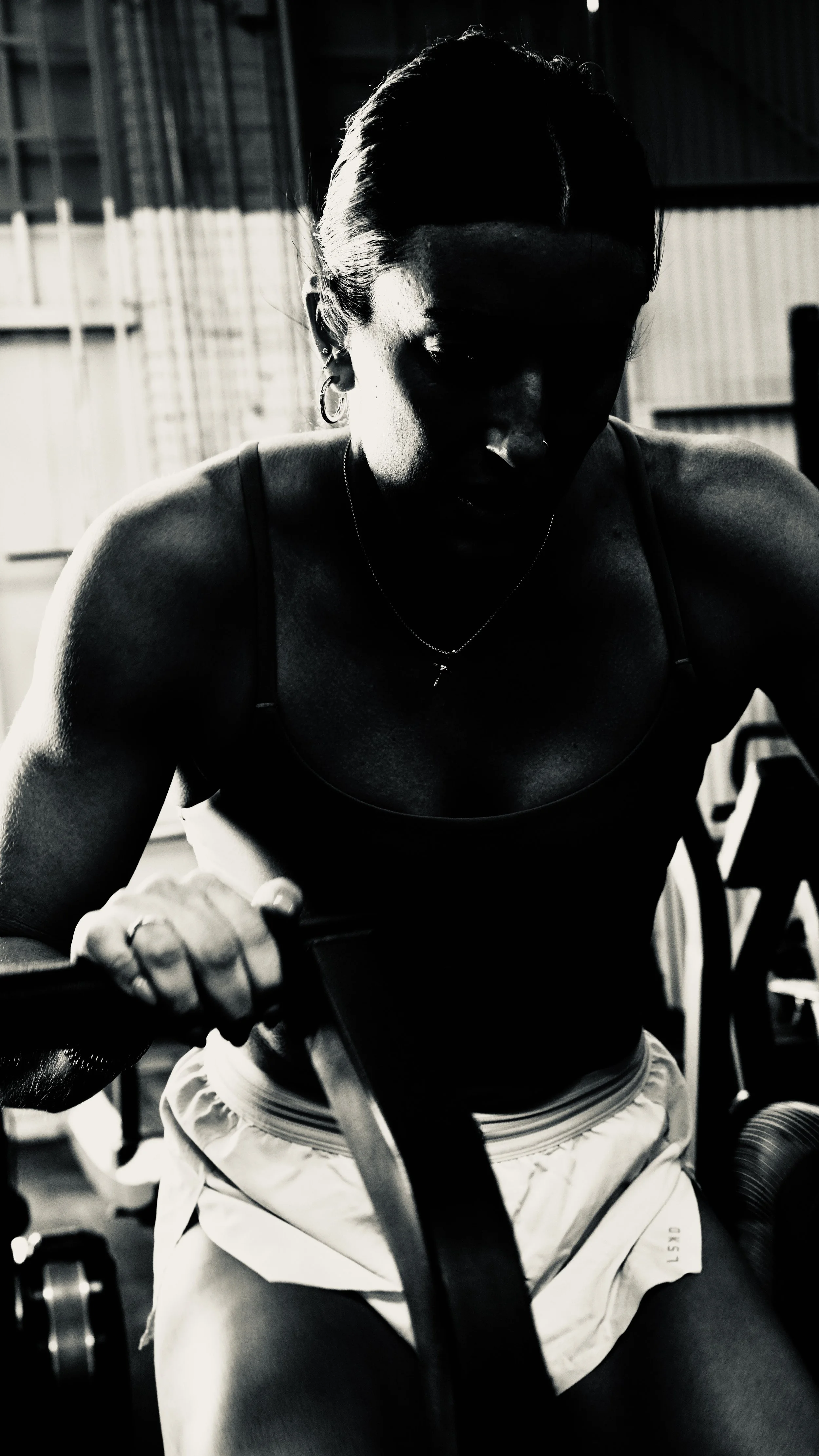 A woman working out at the gym, lifting weights in black and white.