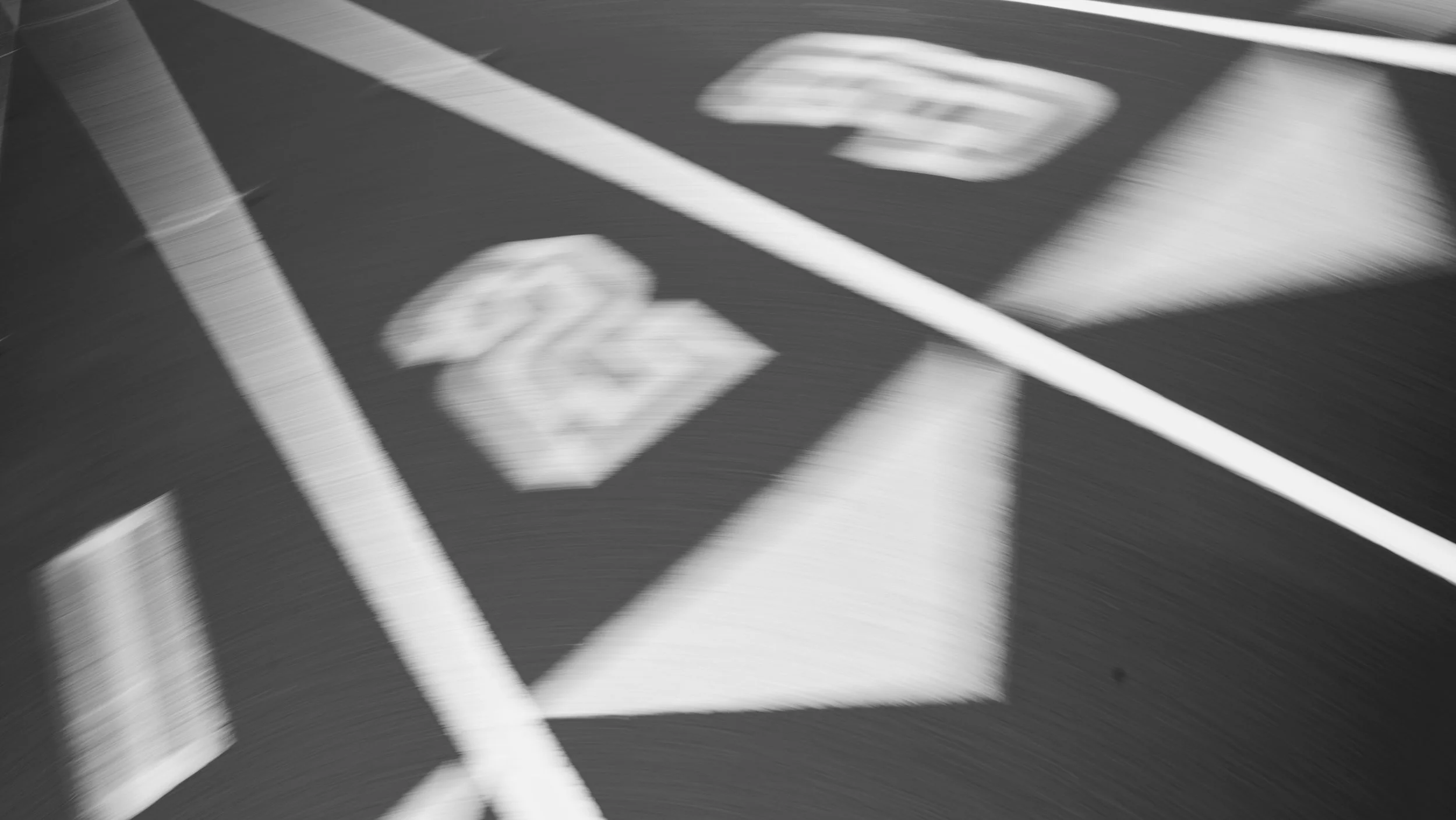 Blurred view of parking lot with painted lines and a bicycle symbol.