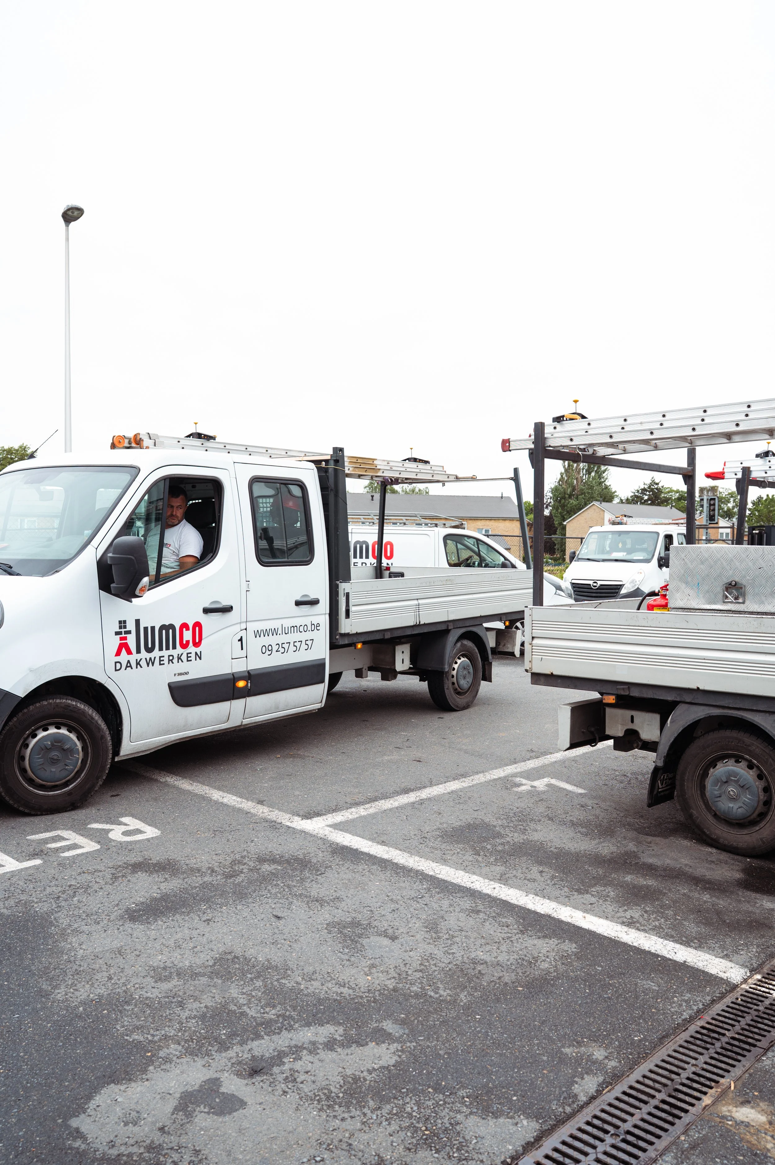 Werkvoertuigen met ladders op een parkeerterrein.