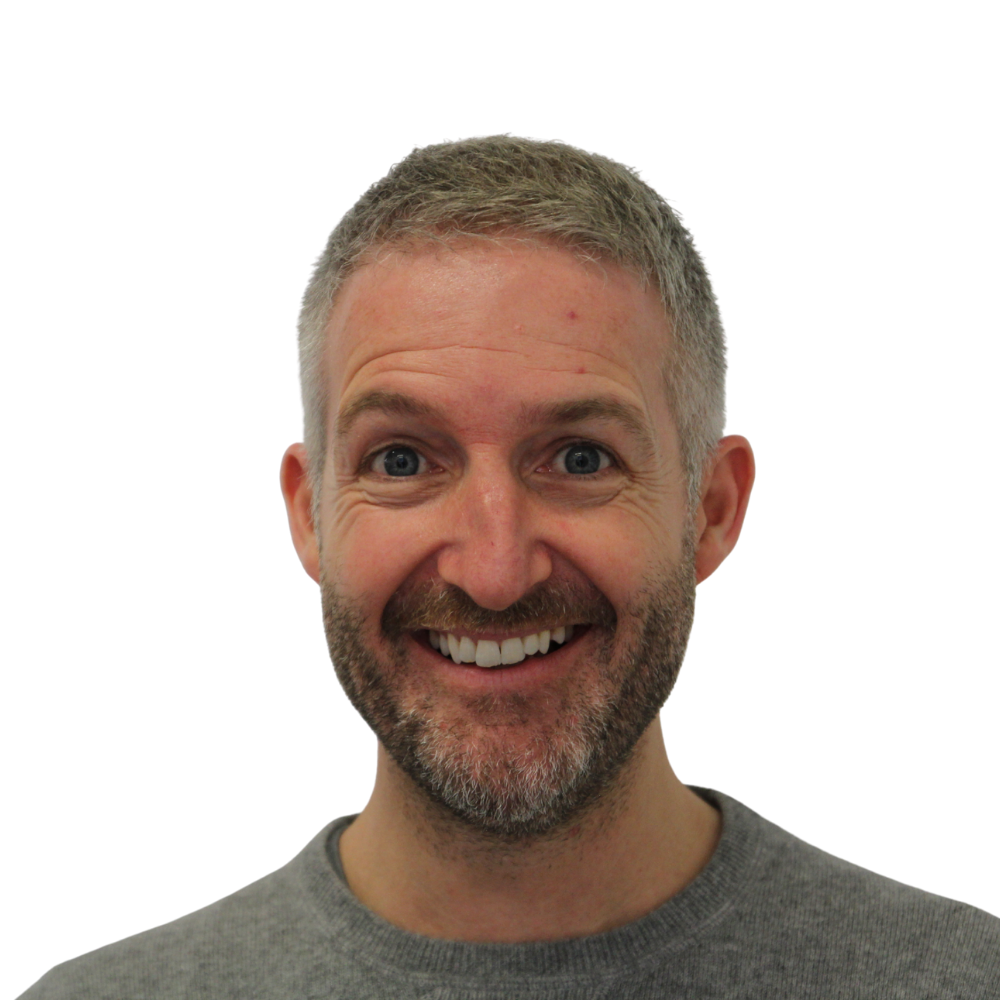 A smiling middle-aged man with short gray hair and a beard, wearing a gray shirt, looking directly at the camera. Stuart Knapman. Qualitative Strategic Intelligence. Man Overboard | Strategic Insight Specialist