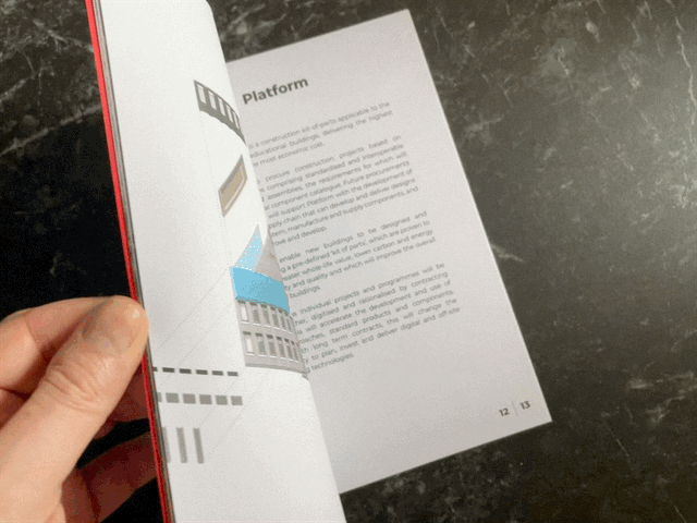 A hand flipping through the final printed GenZero brochure. on a dark surface.