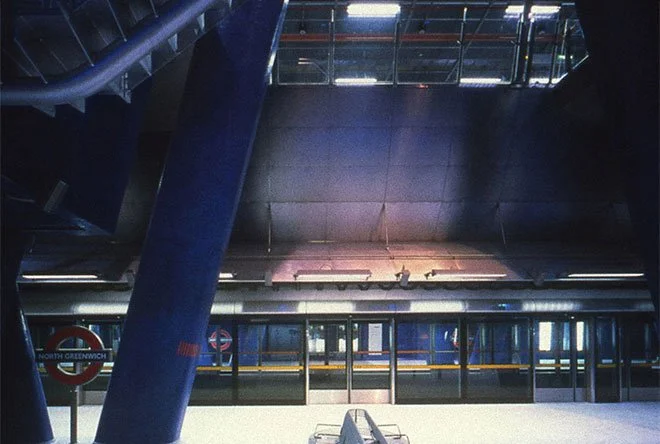 Empty train platform at North Greenwich station with modern architecture and blue structural supports.