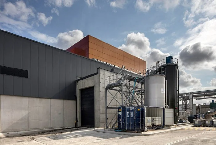 Industrial building with machinery and equipment outdoors under a partly cloudy sky.