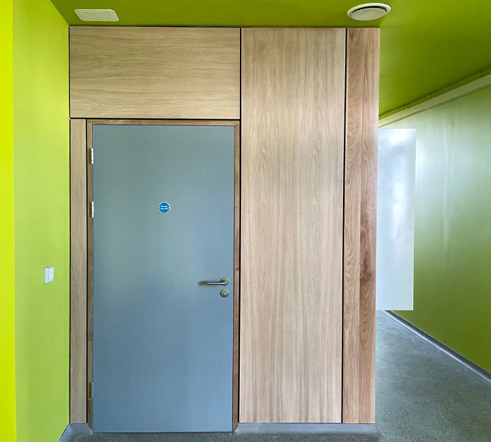 Gray door surrounded by wooden panels in a room with bright green walls and ceiling.