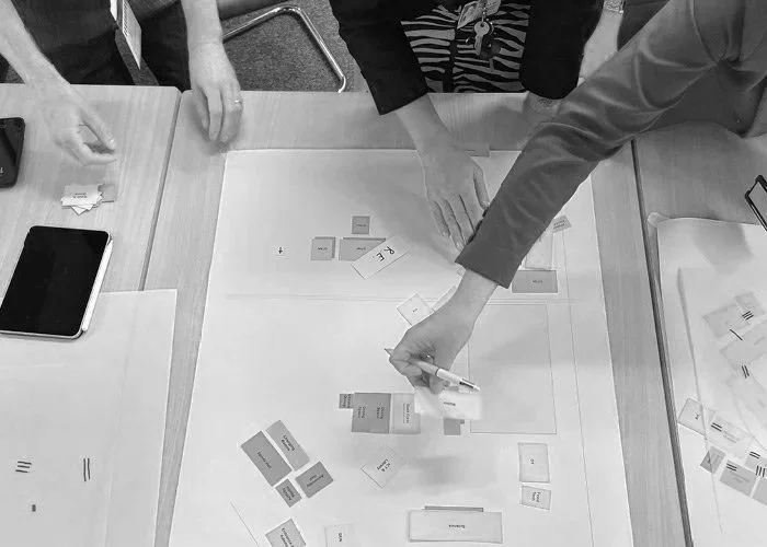 People working together on a table with papers, sticky notes, and a tablet during a collaborative planning or brainstorming session.