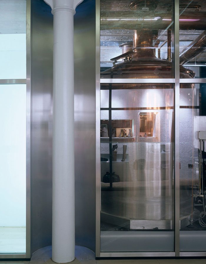 One of the Industrial brewing or tanks inside the Thomas Neal's Cenre building, viewed through glass panels.
