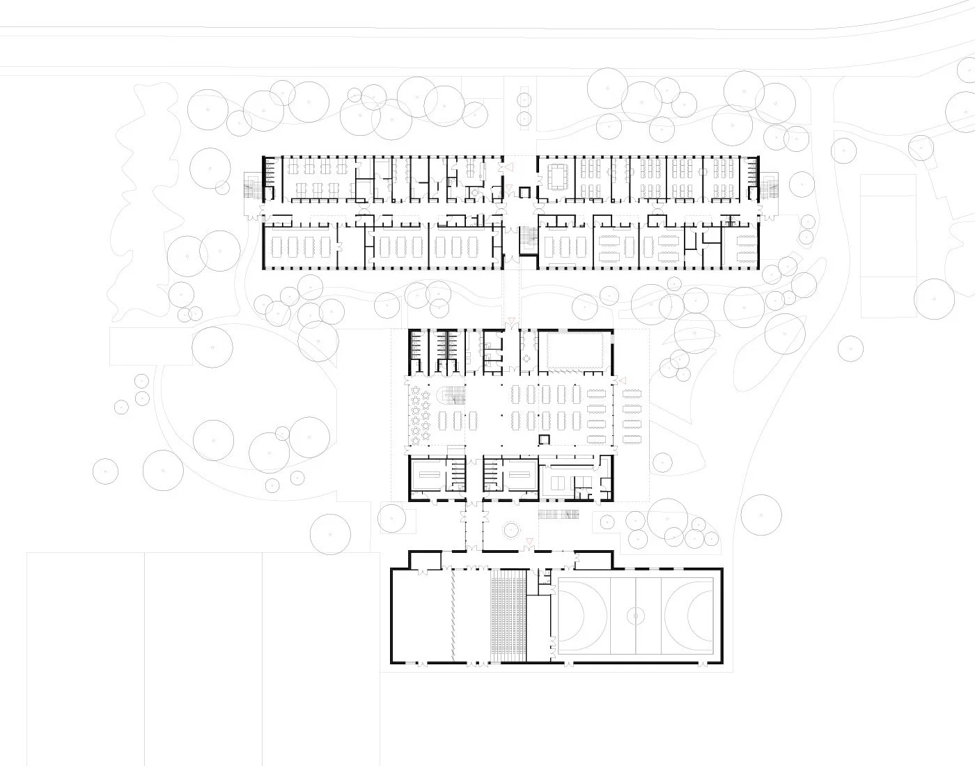 Architectural floor plan of a school or campus building, showing various rooms, hallways, outdoor trees, sports fields, and surrounding landscape.