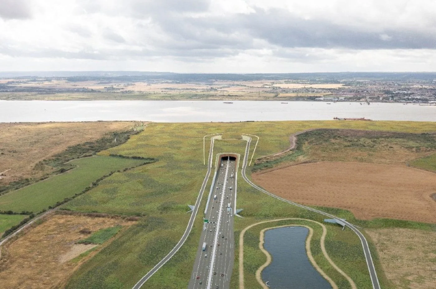 A model of a highway tunnel and surrounding roads in a landscape with grass, farmland, a lake, and a river.