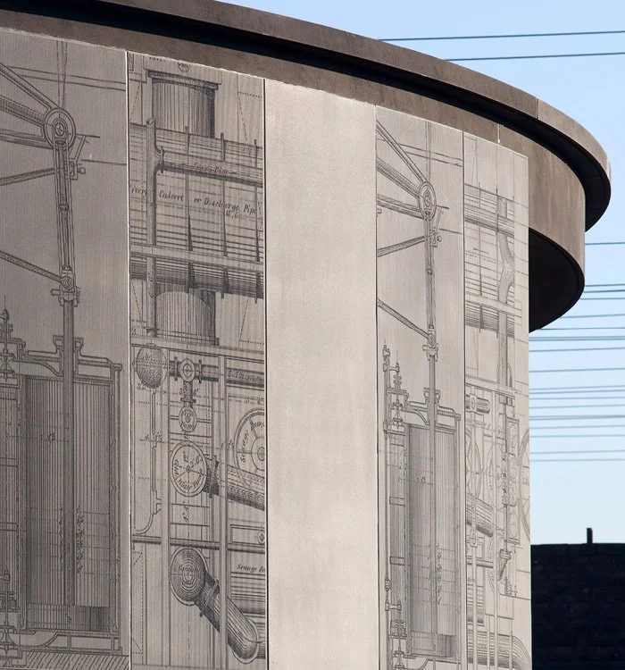 A Close-up of a Pudding Millm Pumping Station's exterior grey pre-cast concrete panels engraved with enlarged versions of Sir Joseph Bazalgette’s Victorian engineering drawings on the wall, featuring mechanical and structural details.