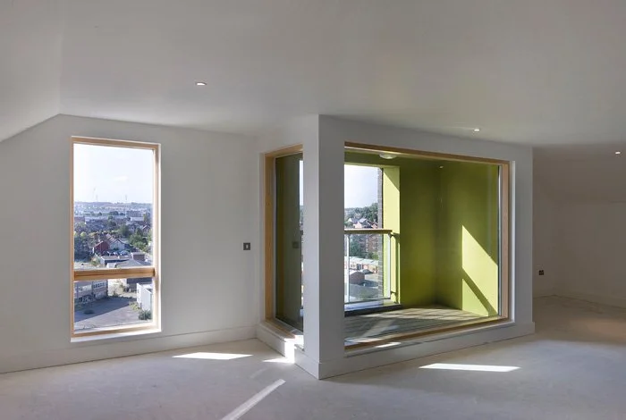 Unfinished room with large windows and a small balcony area, showing a view of a residential neighborhood.