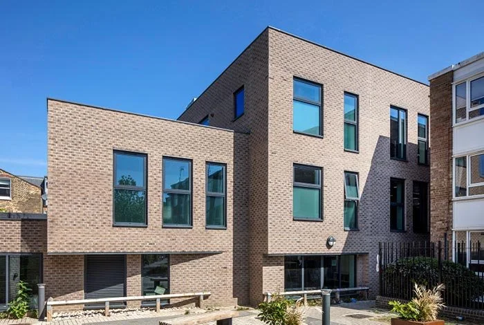 Modern multi-story brick building with large windows and a clear blue sky.