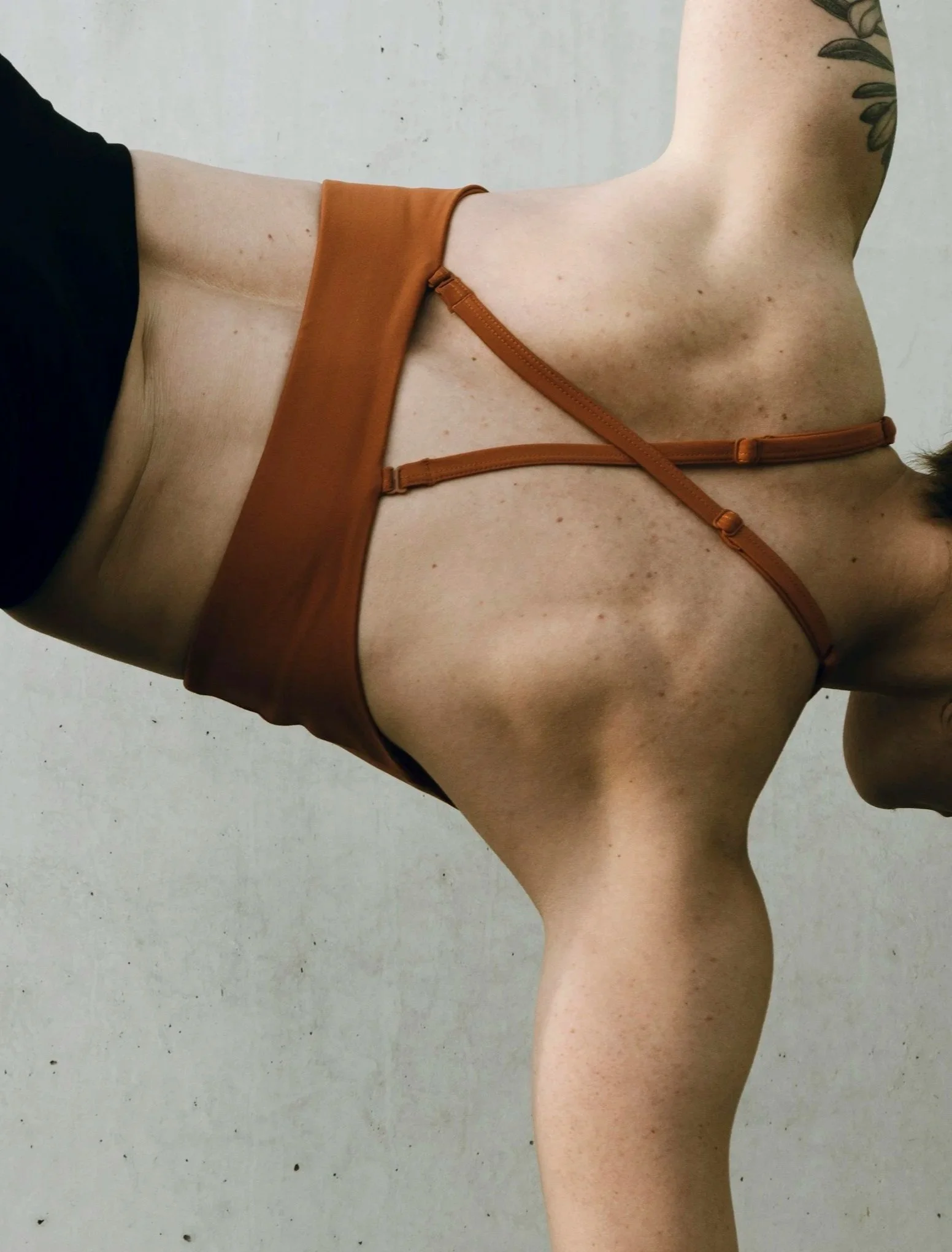 A close up of the back of someone side bending, wearing a workout top