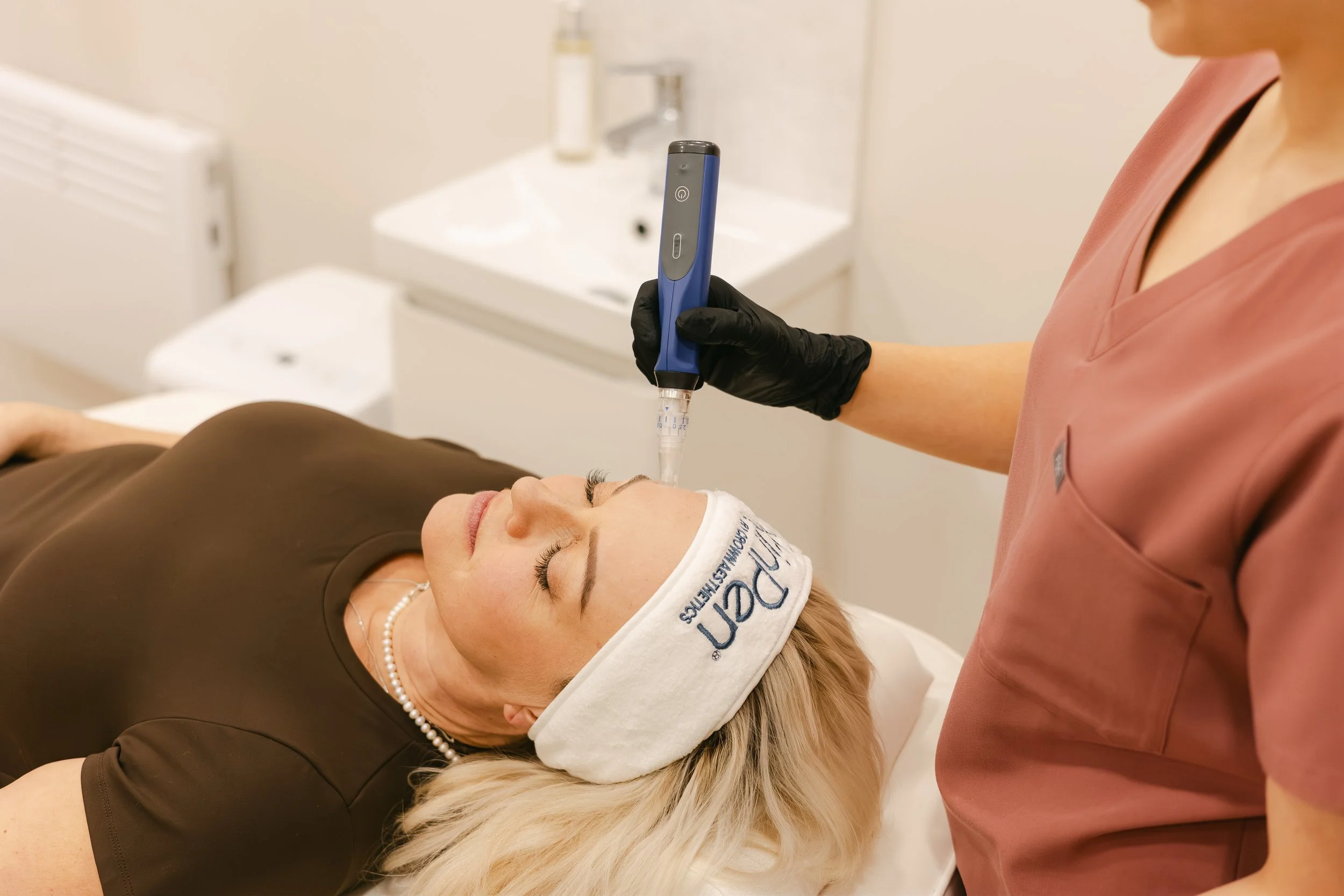 Skinpen treatment for face, Nottingham. A lady lying on a treatment bed having the skinpen facial treatment carried out by a clinic therapist.
