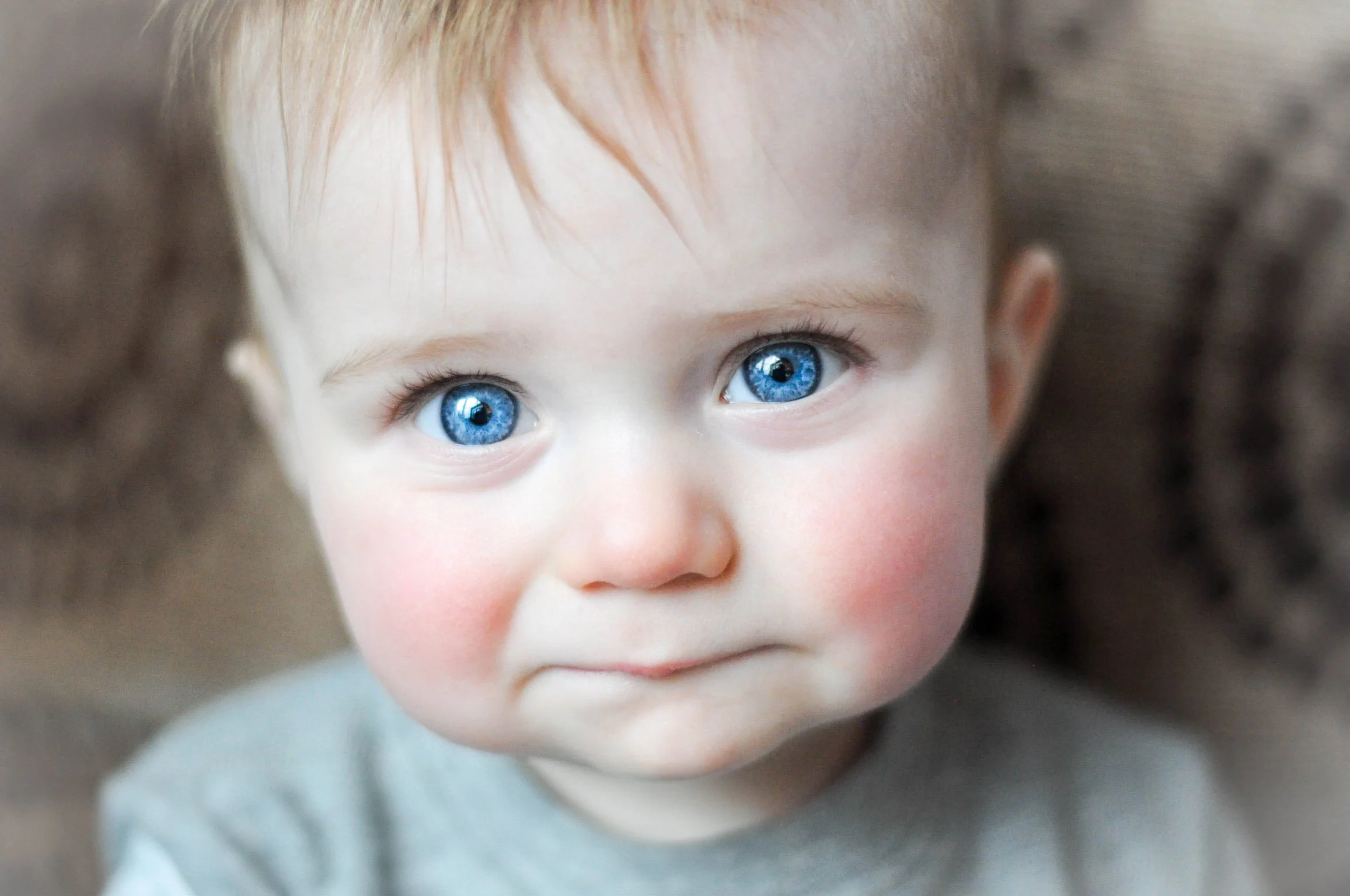 Close-up of a young child's face with bright blue eyes, light skin, and light reddish hair. The child has a serious or pensive expression.