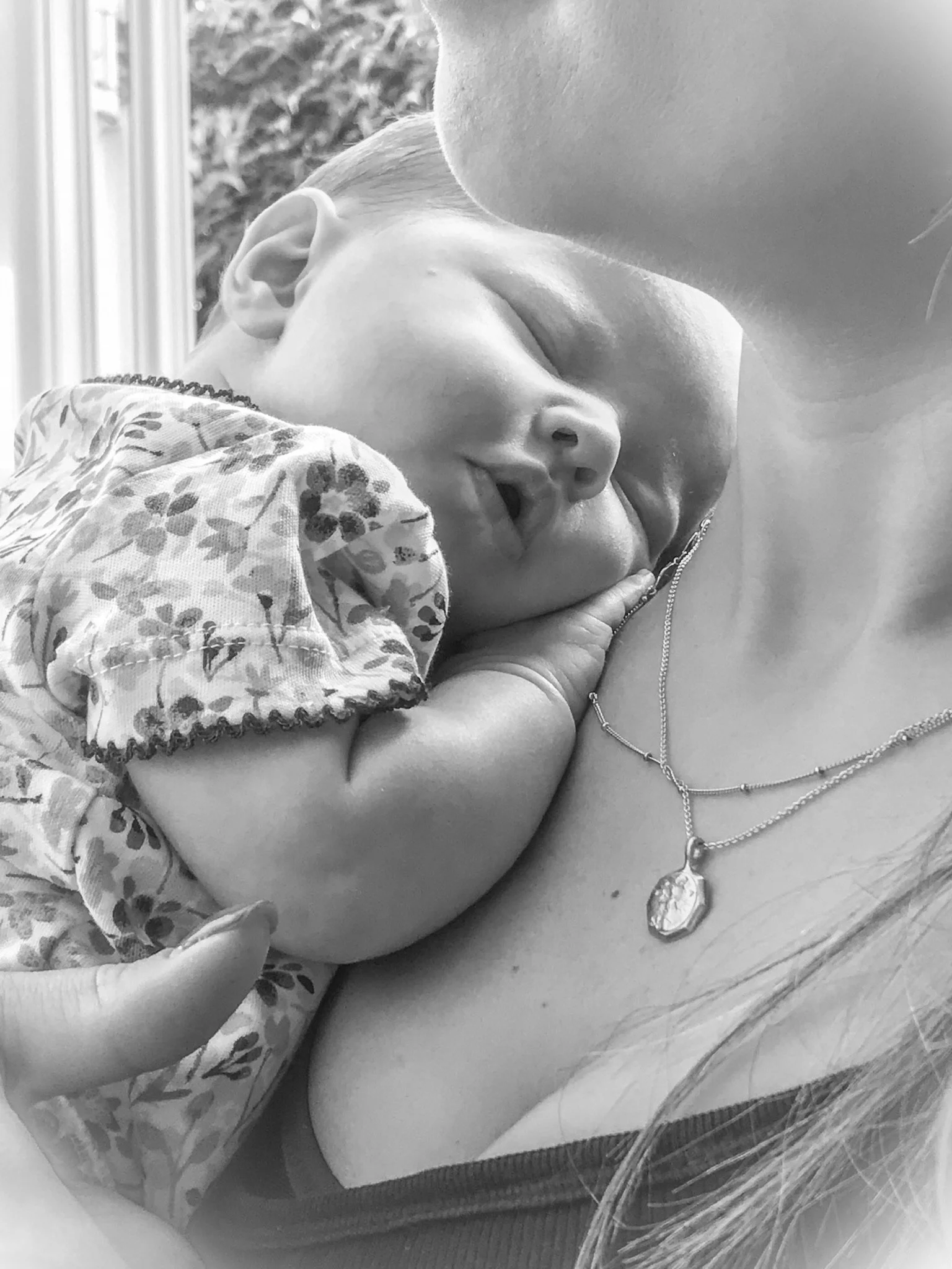 A woman holding a sleeping young child close to her chest, showing an intimate moment of affection and comfort.