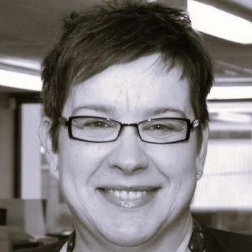 Person wearing glasses and smiling in a black and white photo.