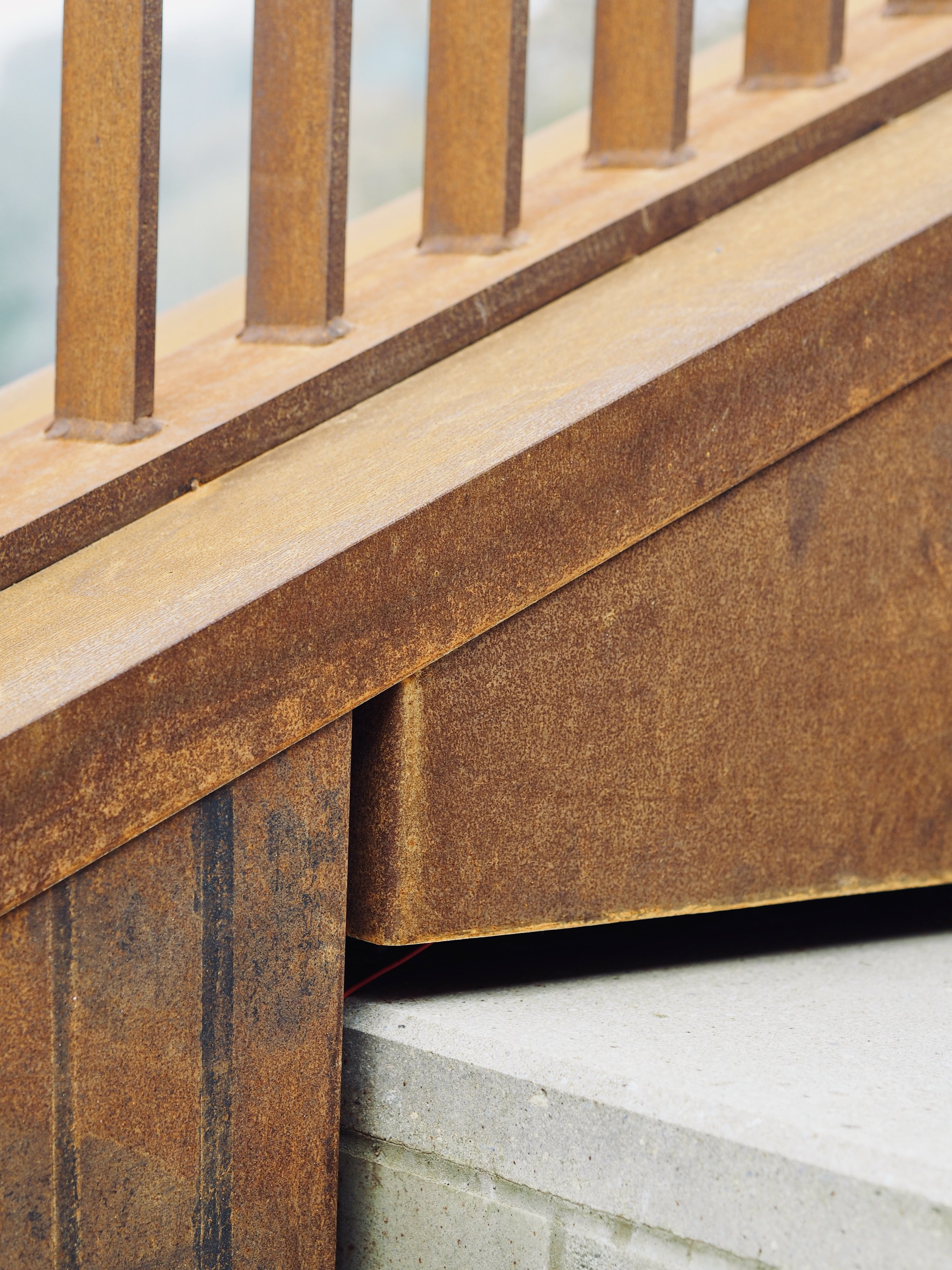 Close-up of a cortex railing and a concrete stains.