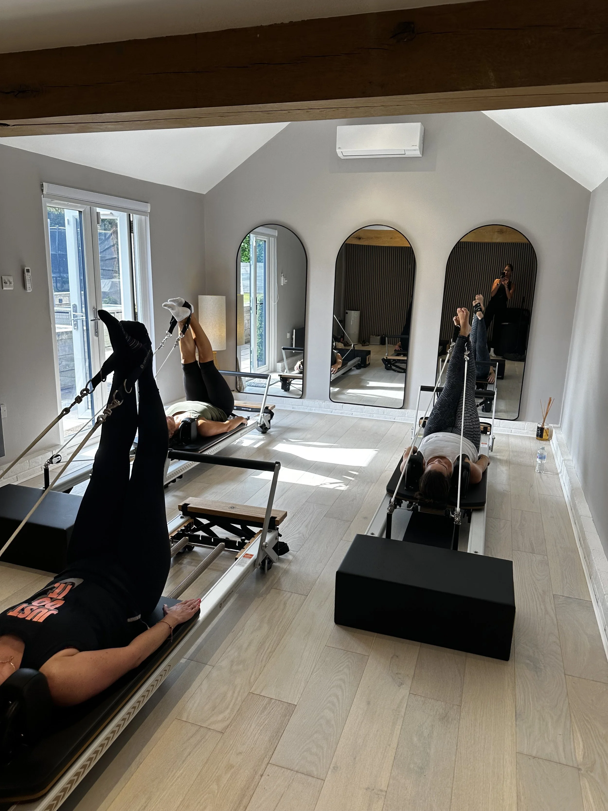 Group Session, 3 clients performing exercises on reformer pilates beds