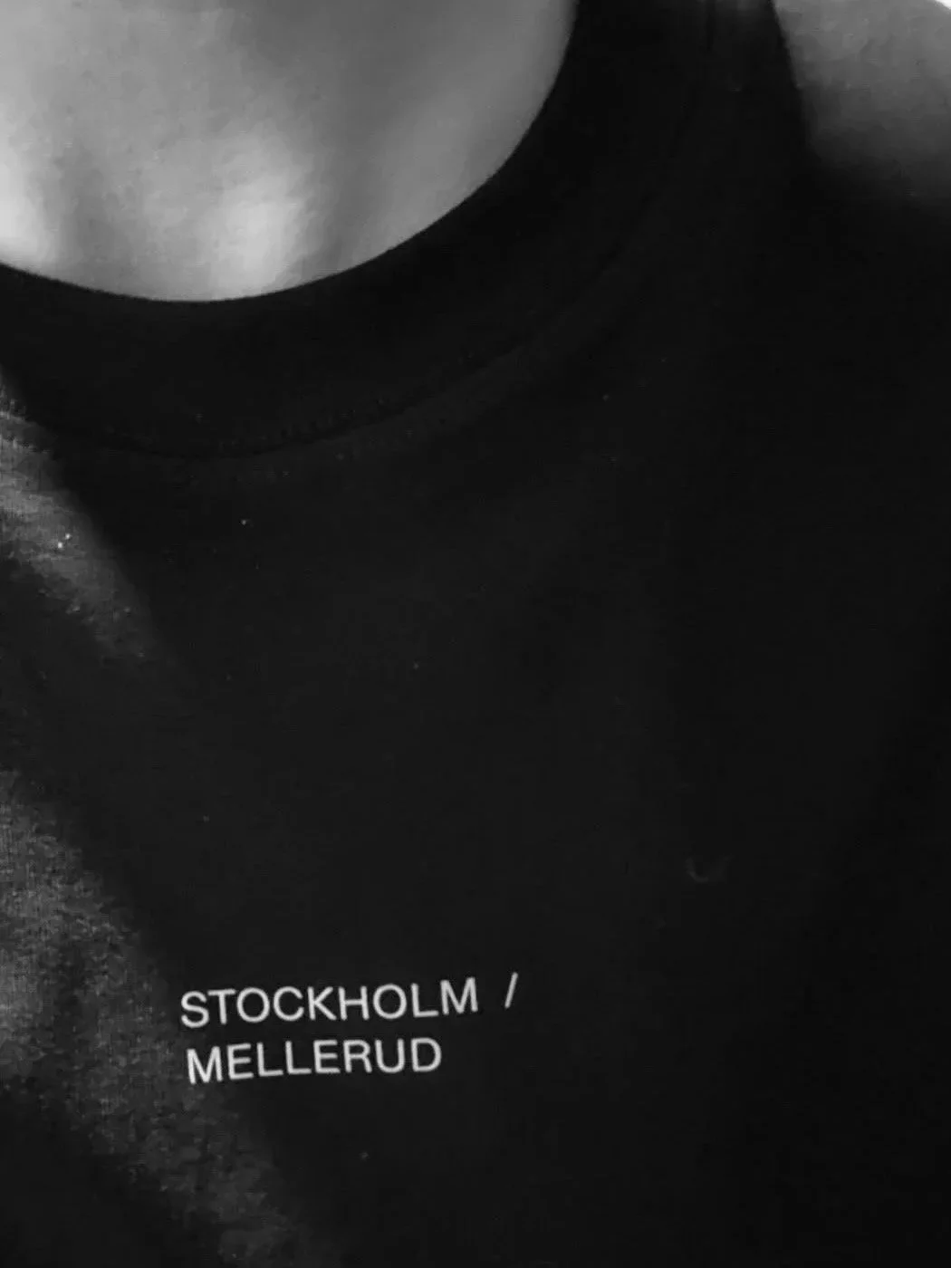 Close-up of a black object with white text that reads 'STOCKHOLM / MELLERUD' in front of a dark surface.