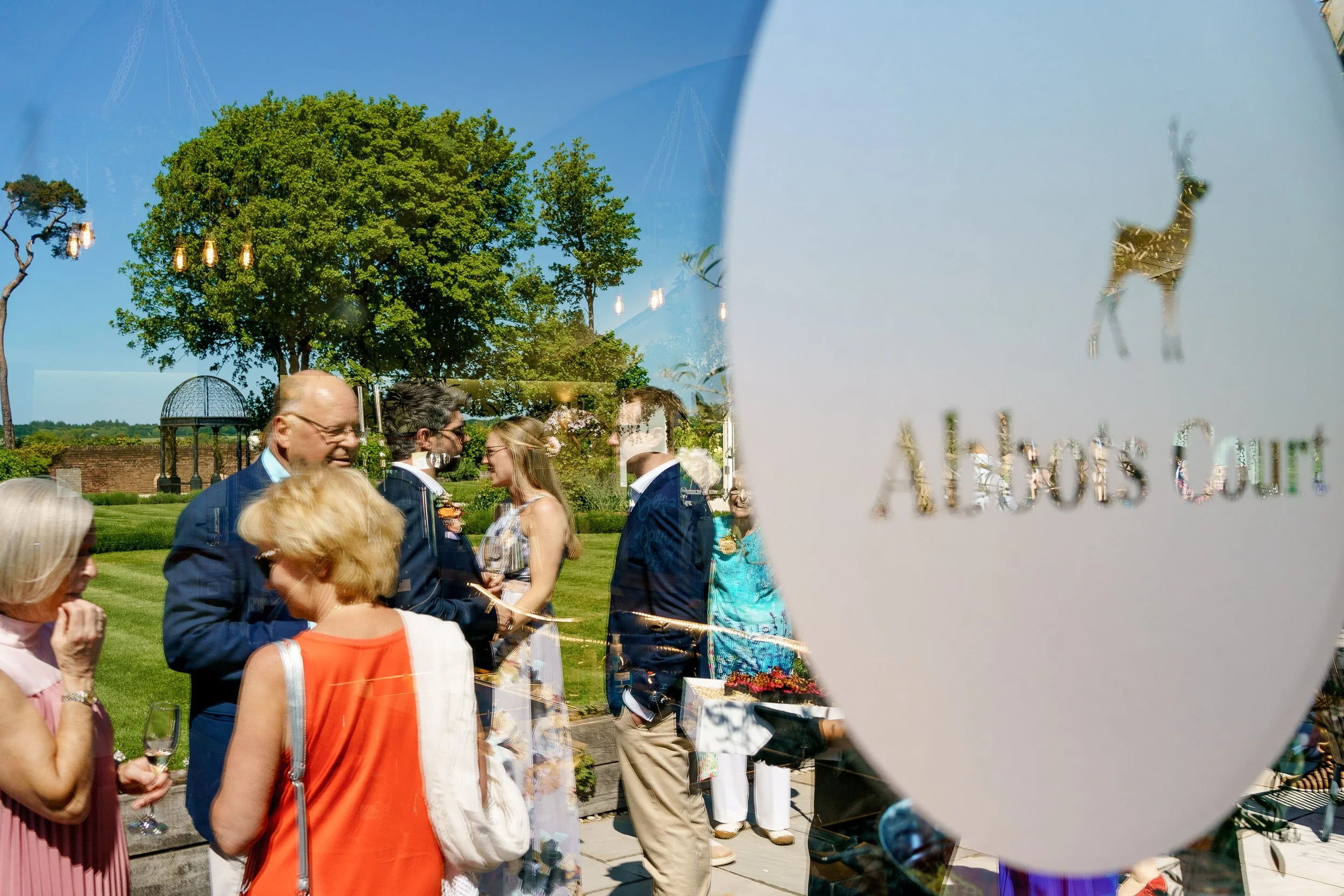 Reflection of a group of people in a glass window with a window graphic that reads "Alabama's Court" and has a silhouette of a deer.
