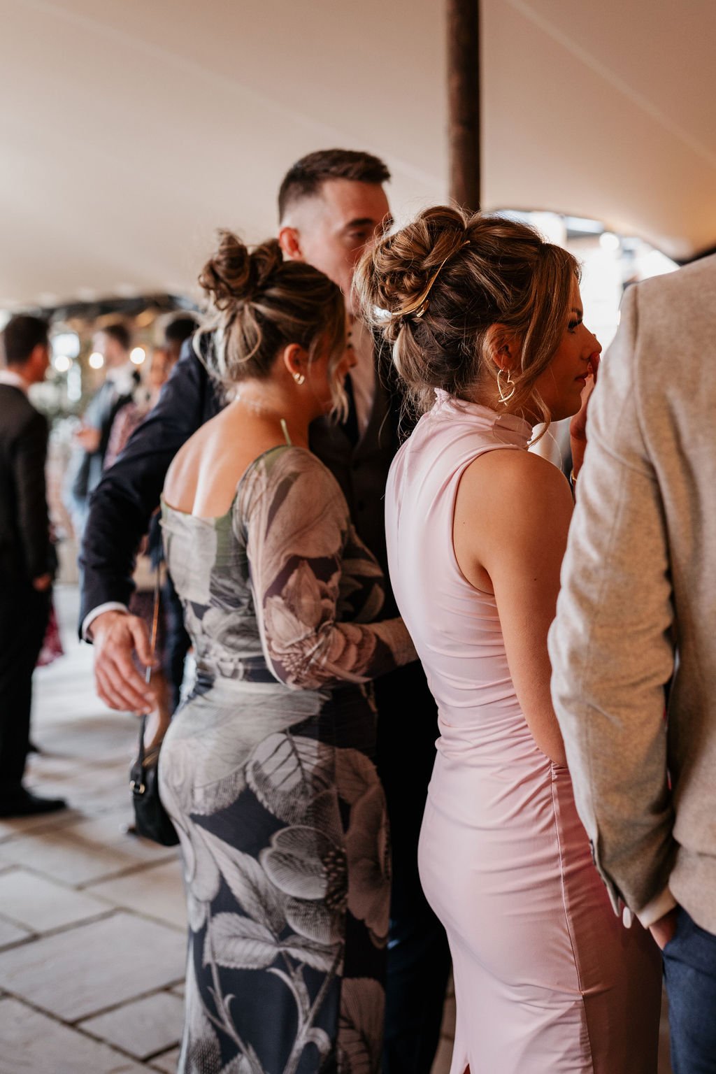 People socializing at a gathering, wearing formal attire. Women in dresses and men in suits.