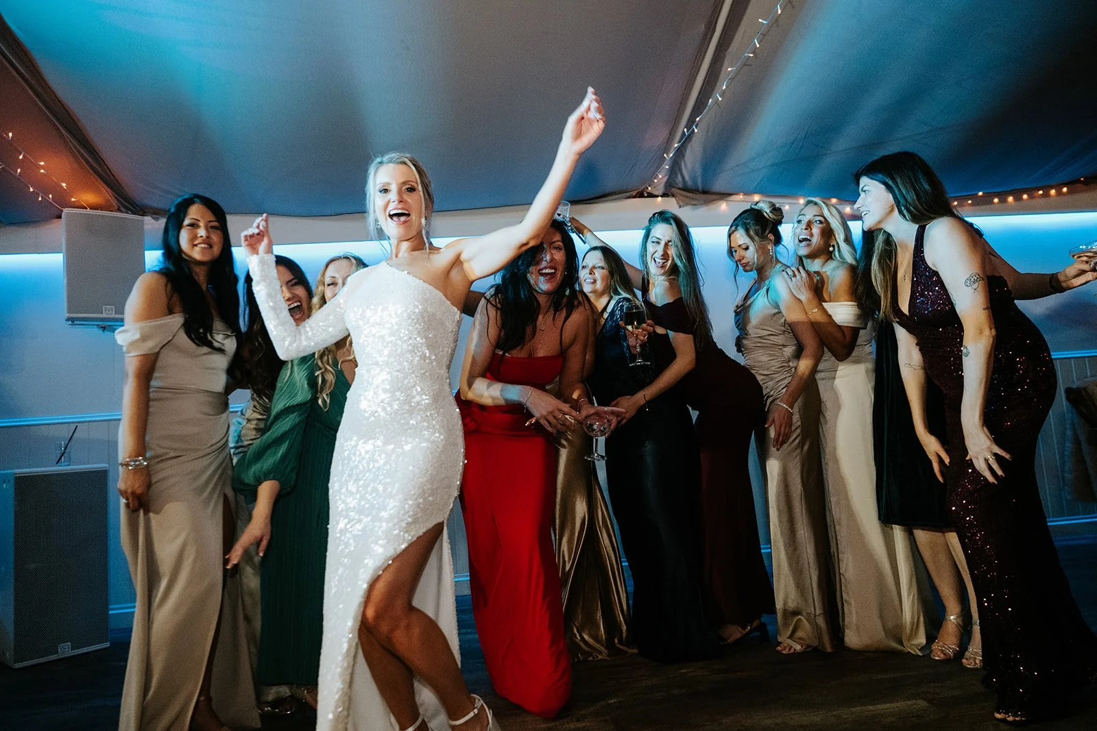 Group of women celebrating at a party, with a woman in a white dress dancing in the foreground.