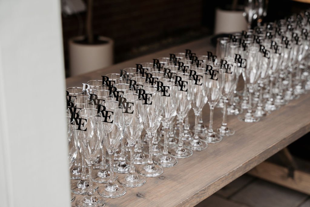 Row of empty champagne flutes with black "RE" logo on wooden table