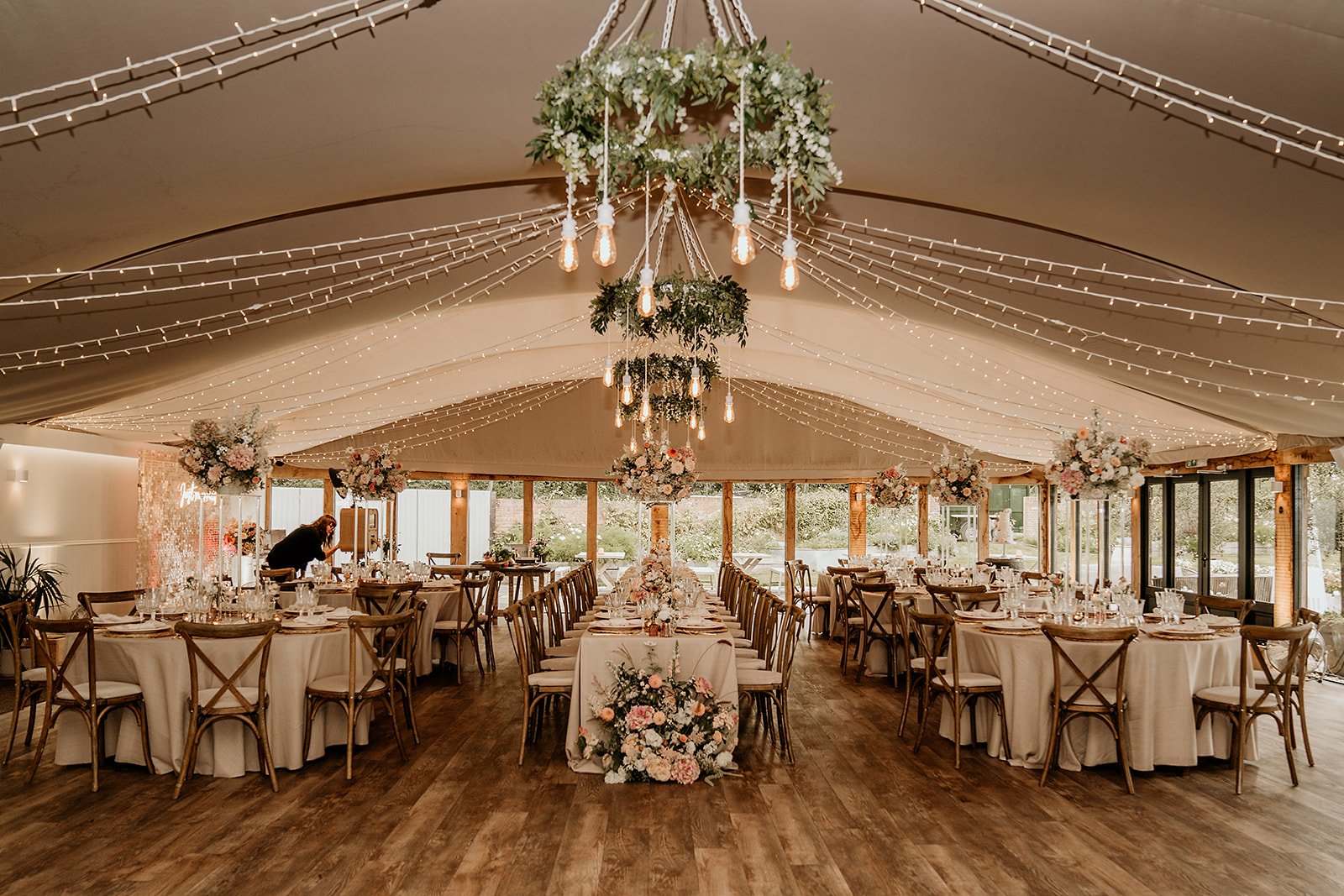 Elegant wedding reception tent with floral centerpieces and string lights.