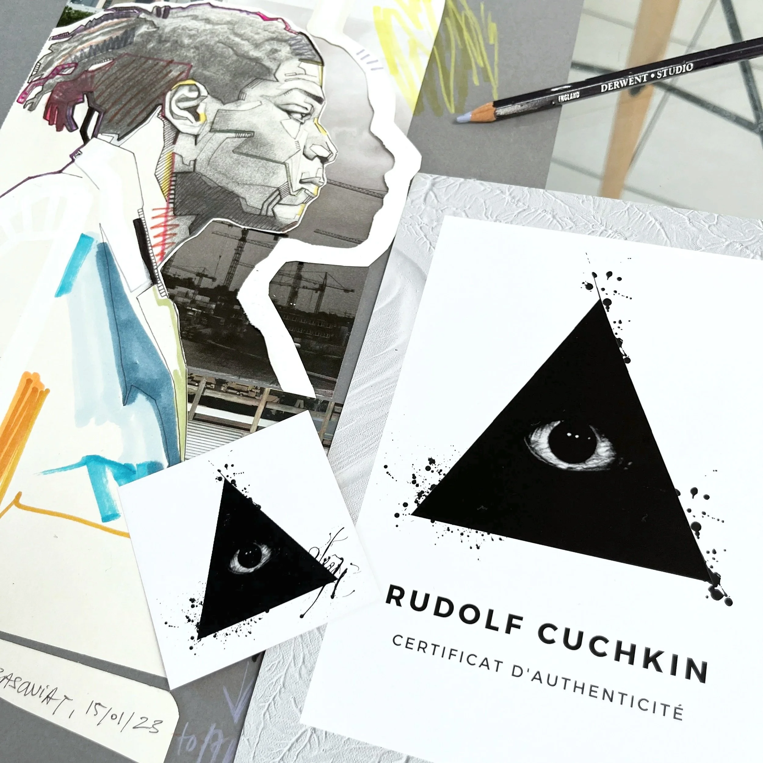Photographie montrant plusieurs documents, dont certains avec un dessin artistique en style collage représentant une tête de profil avec des lignes et détails abstraits, ainsi qu'un certificat d'authenticité. La mise en page suggère un espace de travail ou d'art avec différents éléments empilés ou disposés.