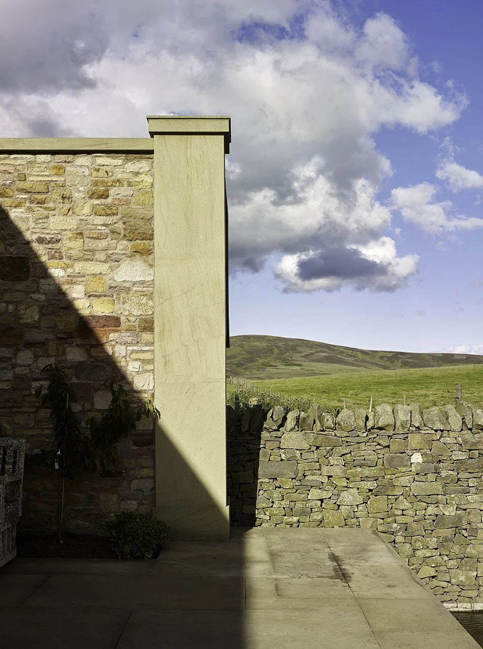 Stone garden wall and courtyard terrace adjoining the orangery within the estate landscape.