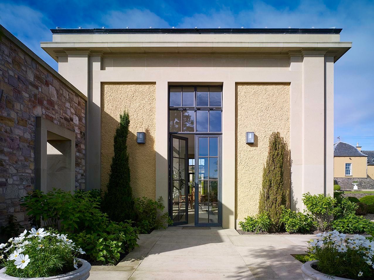 Entrance to the orangery framed by formal planting and classical architectural detailing
