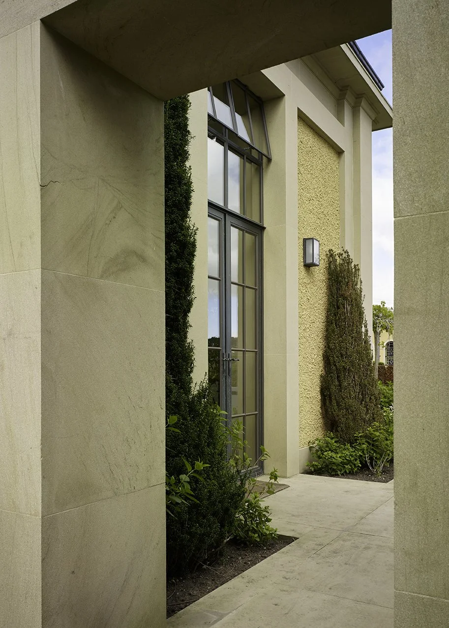 Covered entrance passage leading to the orangery with stone surrounds and landscaped planting.