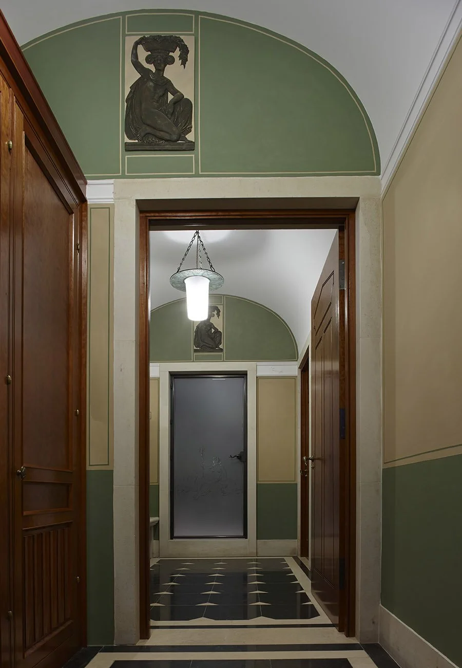 Interior corridor with classical arch, painted wall panels and bespoke timber joinery within the Gloucestershire bath house.