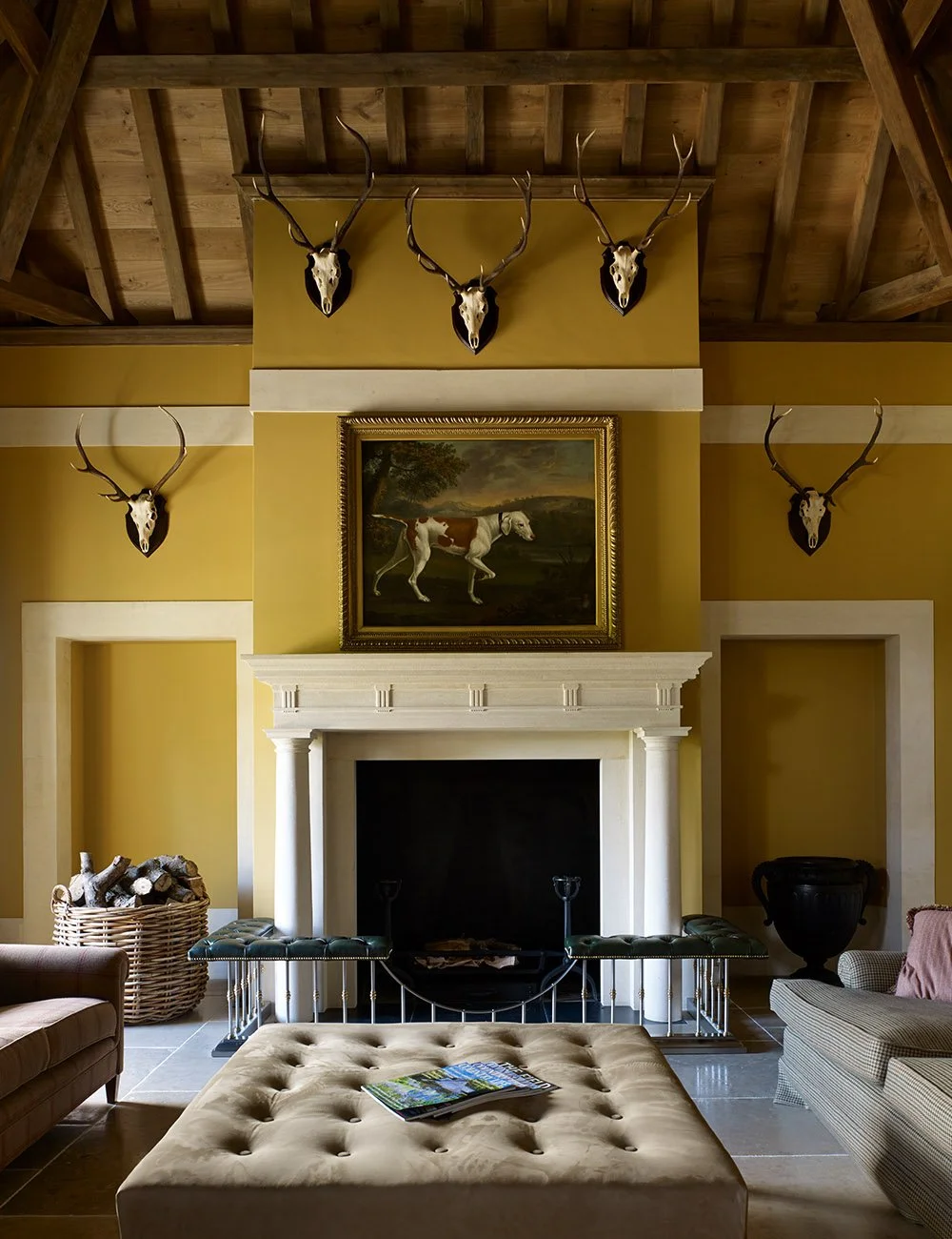 Classical fireplace in the reception room of the Shooting Lodge in Gloucestershire with timber beams and traditional country house detailing.