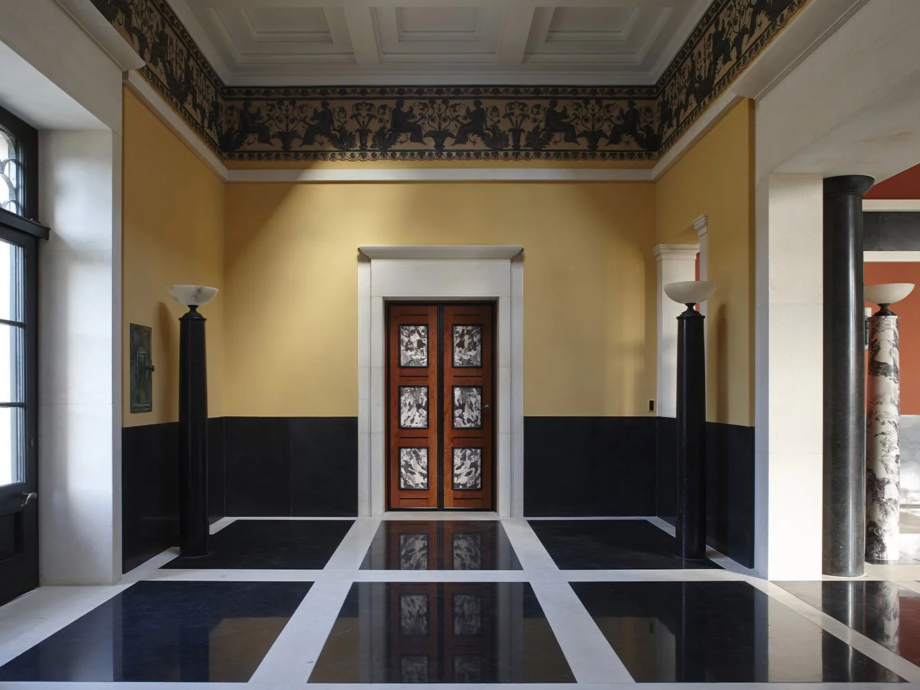 Decorative timber doorway with classical stone surround and geometric marble floor within the Gloucestershire bath house.