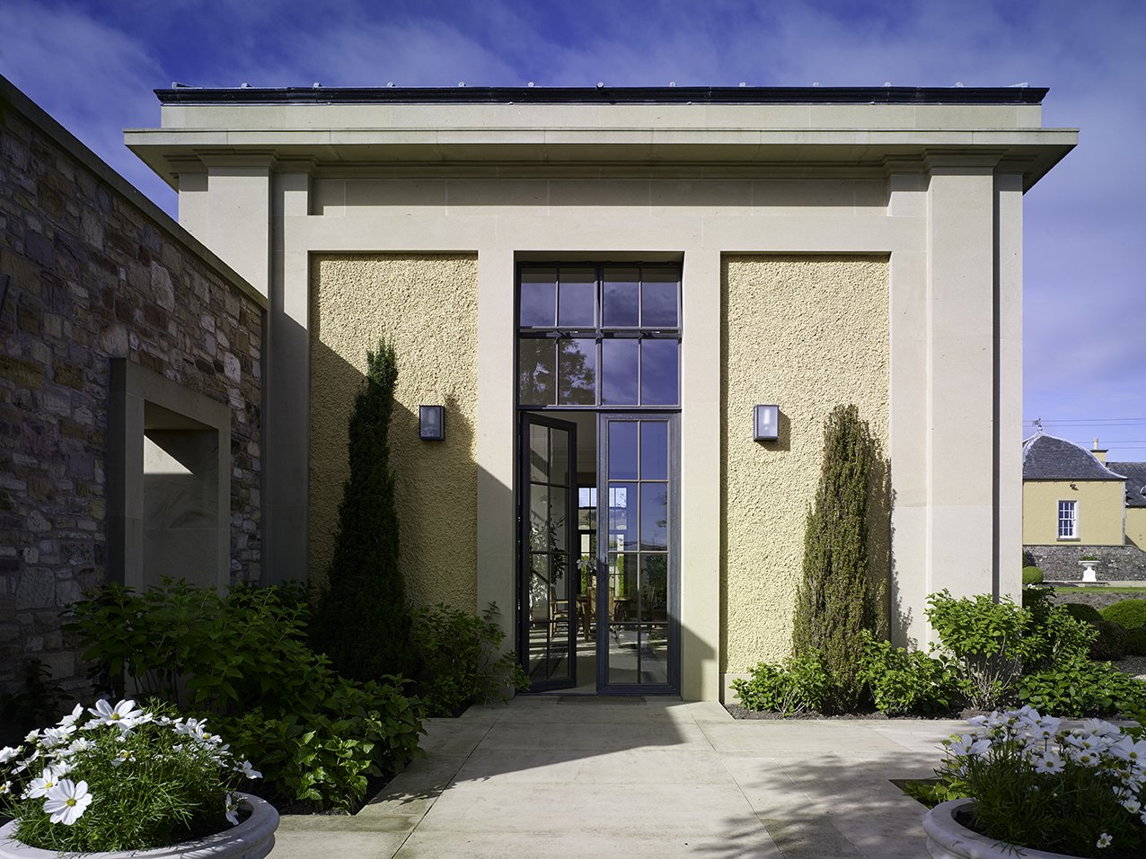 Entrance to the orangery framed by formal planting and classical architectural detailing