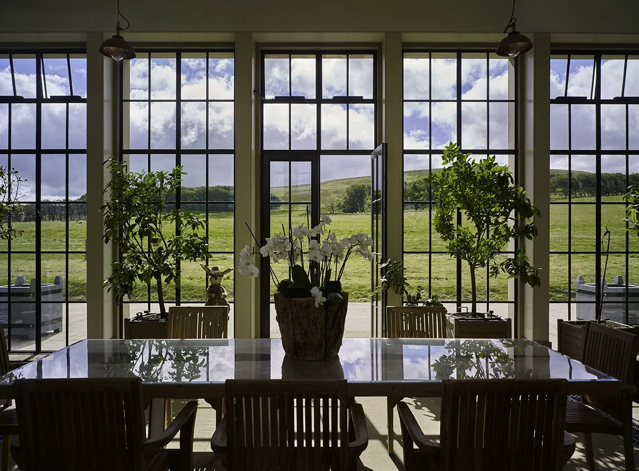 View through the orangery’s glazed façade towards the surrounding countryside and formal gardens.
