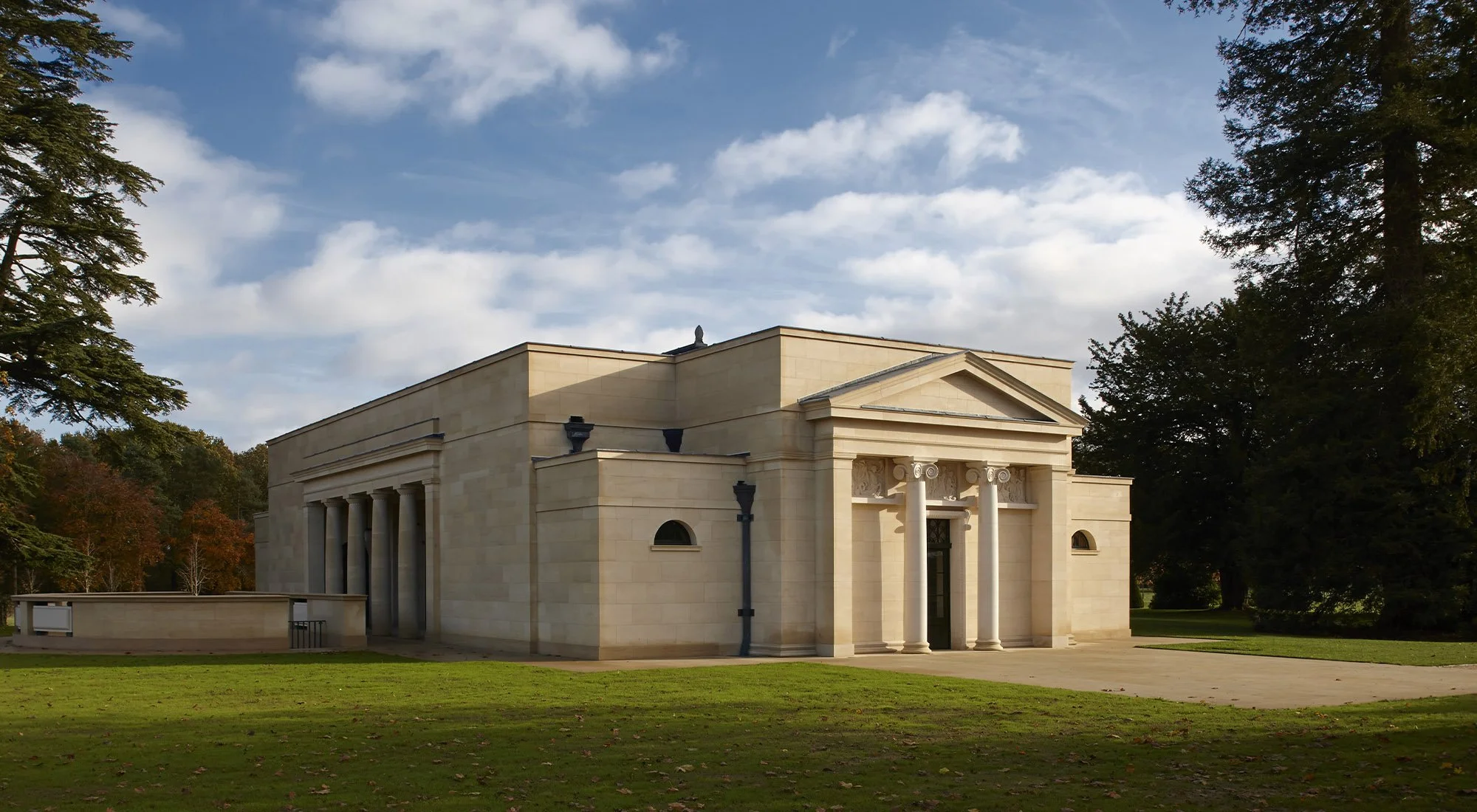 Classical stone bath house in Gloucestershire with Ionic portico, limestone facade and landscaped parkland setting.