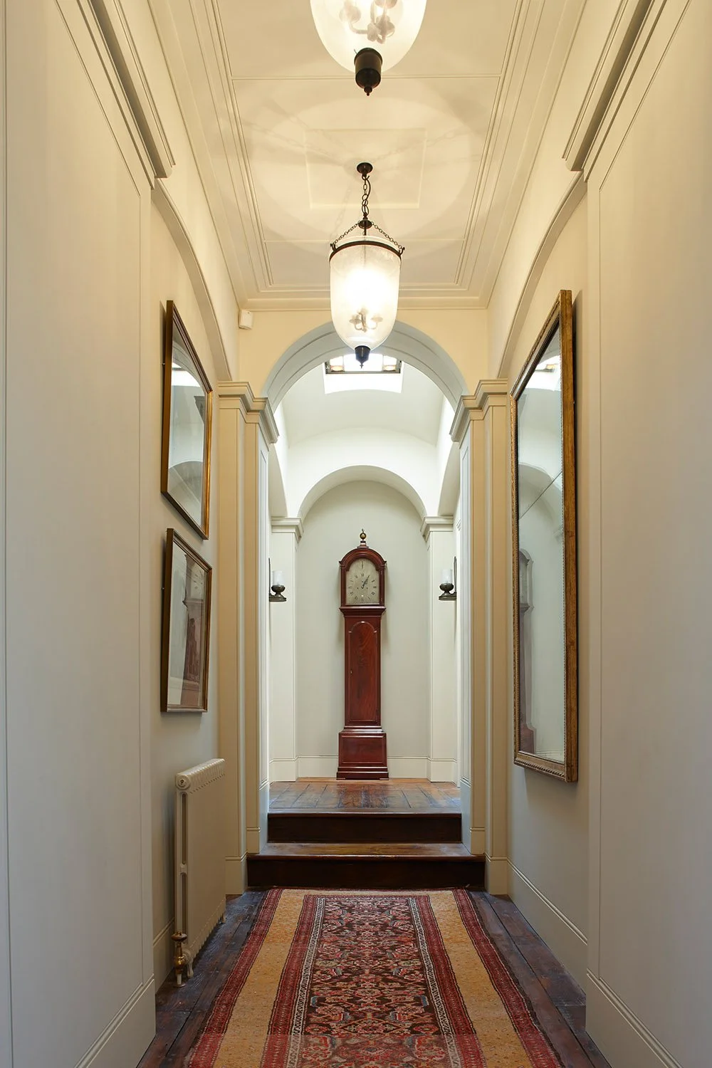 Barrel-vaulted corridor within a historic London apartment featuring classical detailing, decorative lighting and period finishes.