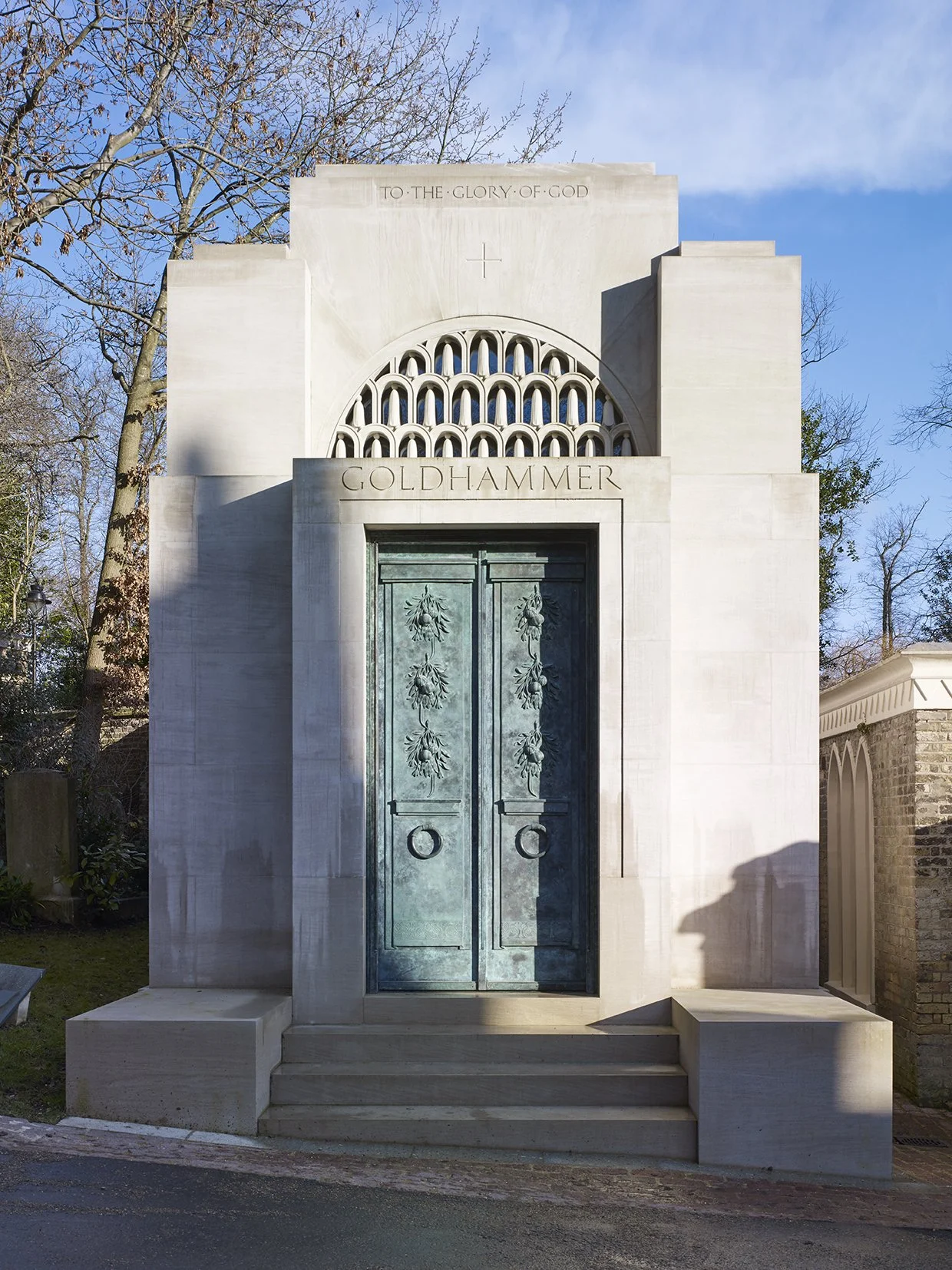 Monumental entrance to a classical stone mausoleum featuring bronze doors and carved architectural detailing.