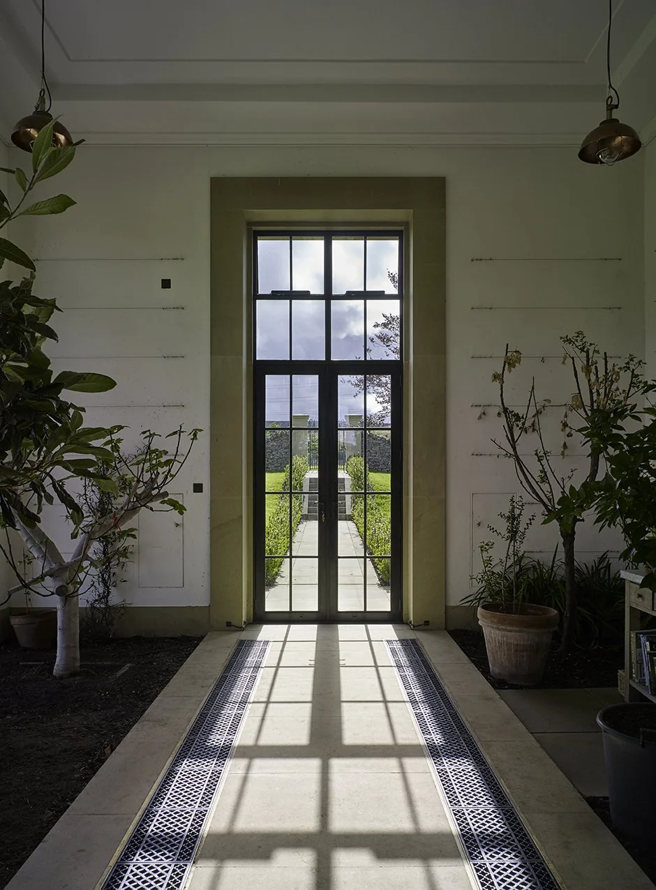 View through the orangery entrance aligned with the formal garden axis beyond.