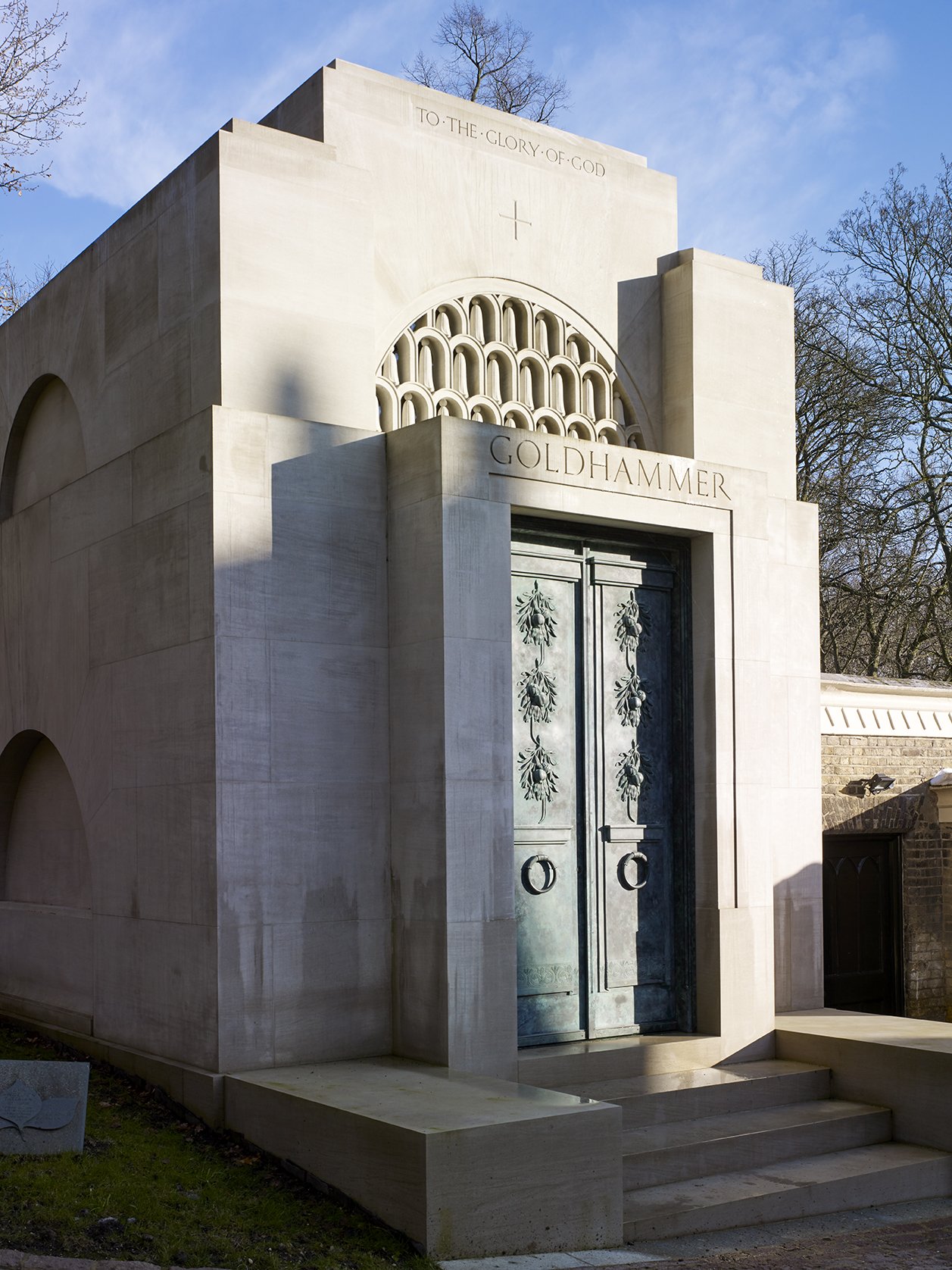 Three-quarter view of a classical stone mausoleum showing its monumental form, arched side openings and traditional craftsmanship.