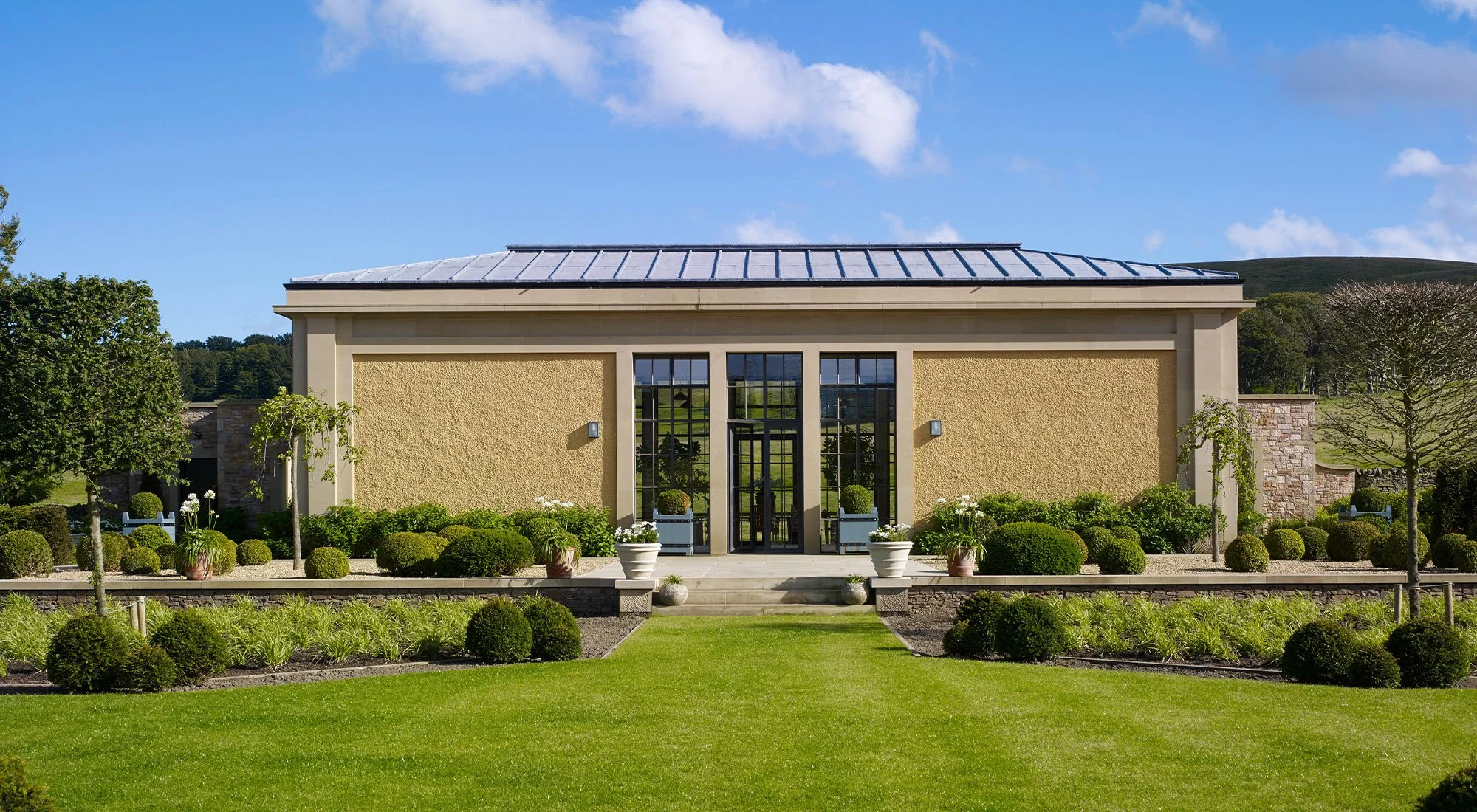 Classical orangery with symmetrical façade, central glazed entrance and formal landscaped gardens in the north of Britain.