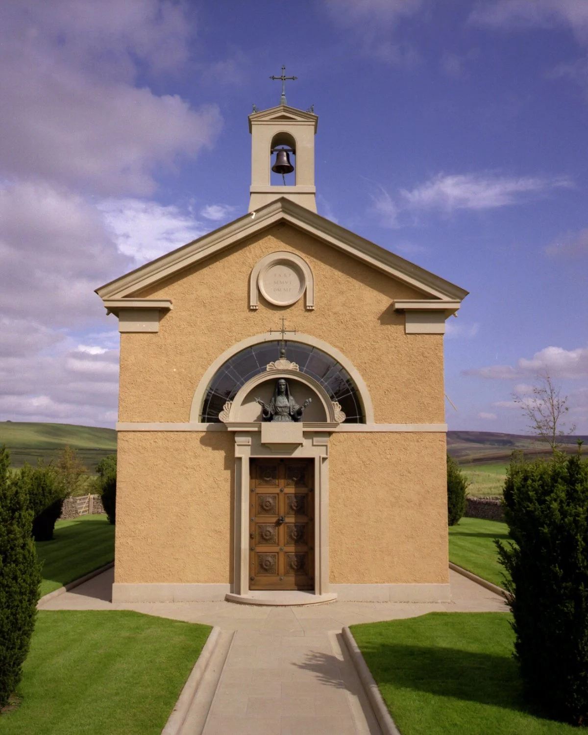 Front elevation of a private Catholic chapel in the north of Britain, featuring classical detailing, a bell tower, and traditional stone surrounds.
