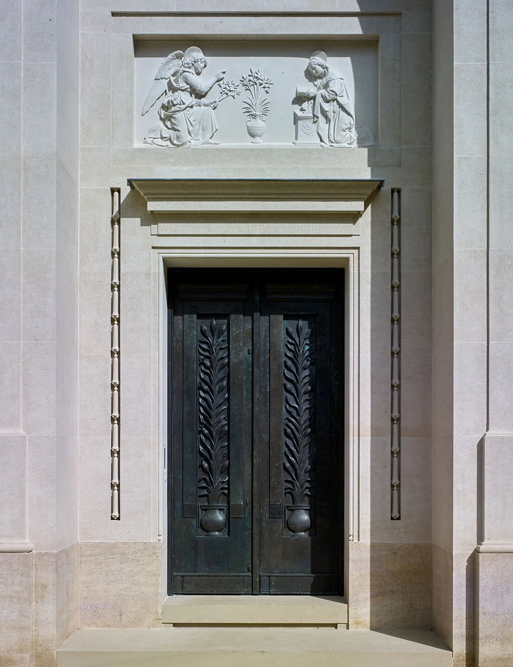 Classical chapel entrance with bronze doors and hand-carved Annunciation stone relief at Williamstrip.