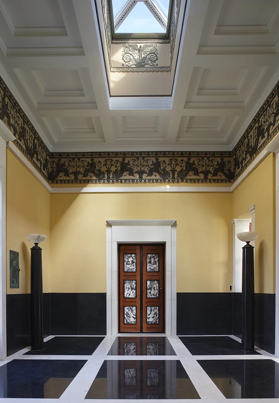 Entrance hall featuring a decorative classical frieze, coffered ceiling and geometric stone flooring within the bath house.