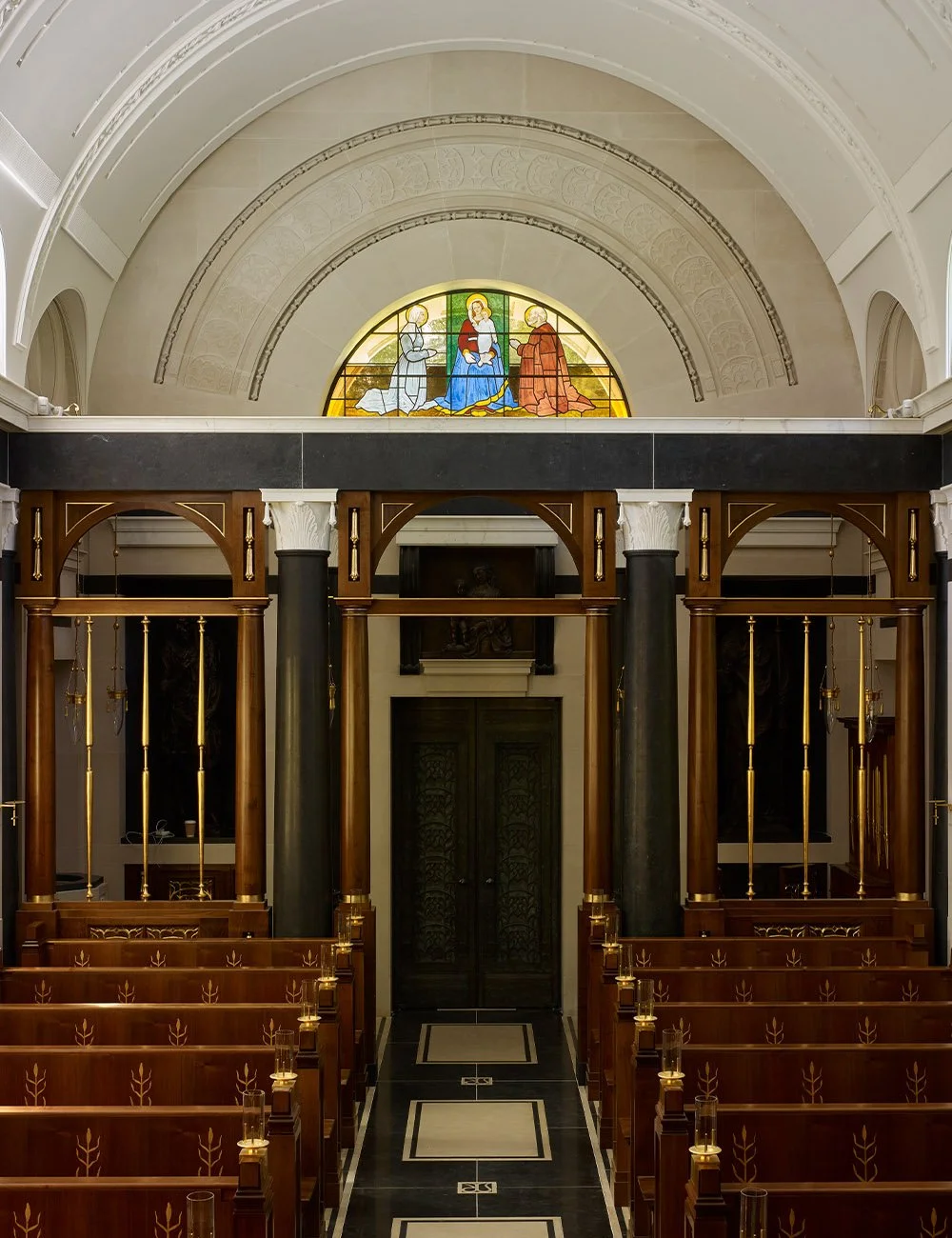 View from the sanctuary towards the entrance showing timber pews, stained glass and vaulted ceilings at the Williamstrip chapel.