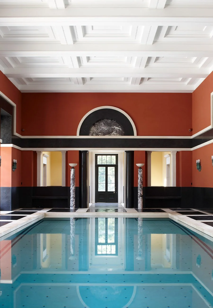 Swimming pool hall within a classical bath house, showing coffered ceilings, marble detailing and the principal entrance beyond.