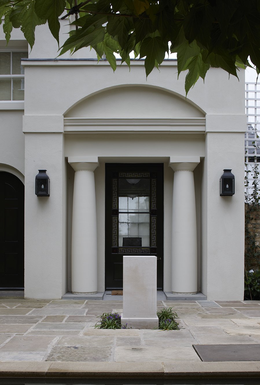 Classical entrance portico with Tuscan columns and stone courtyard paving at London courtyard house by Craig Hamilton Architects.